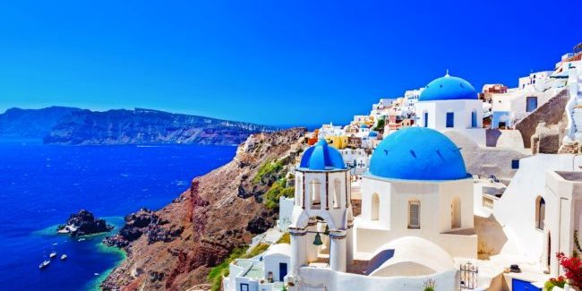 Oia town on Santorini island, Greece. Traditional and famous houses and churches with blue domes over the Caldera, Aegean sea