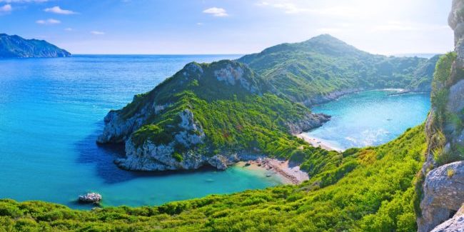 Beautiful summertime panoramic seascape. View of the cliff into the crystal clear azure sea bay and distant islands. Unique secluded beach. Agios Stefanos cape. Afionas. Corfu. Greece.