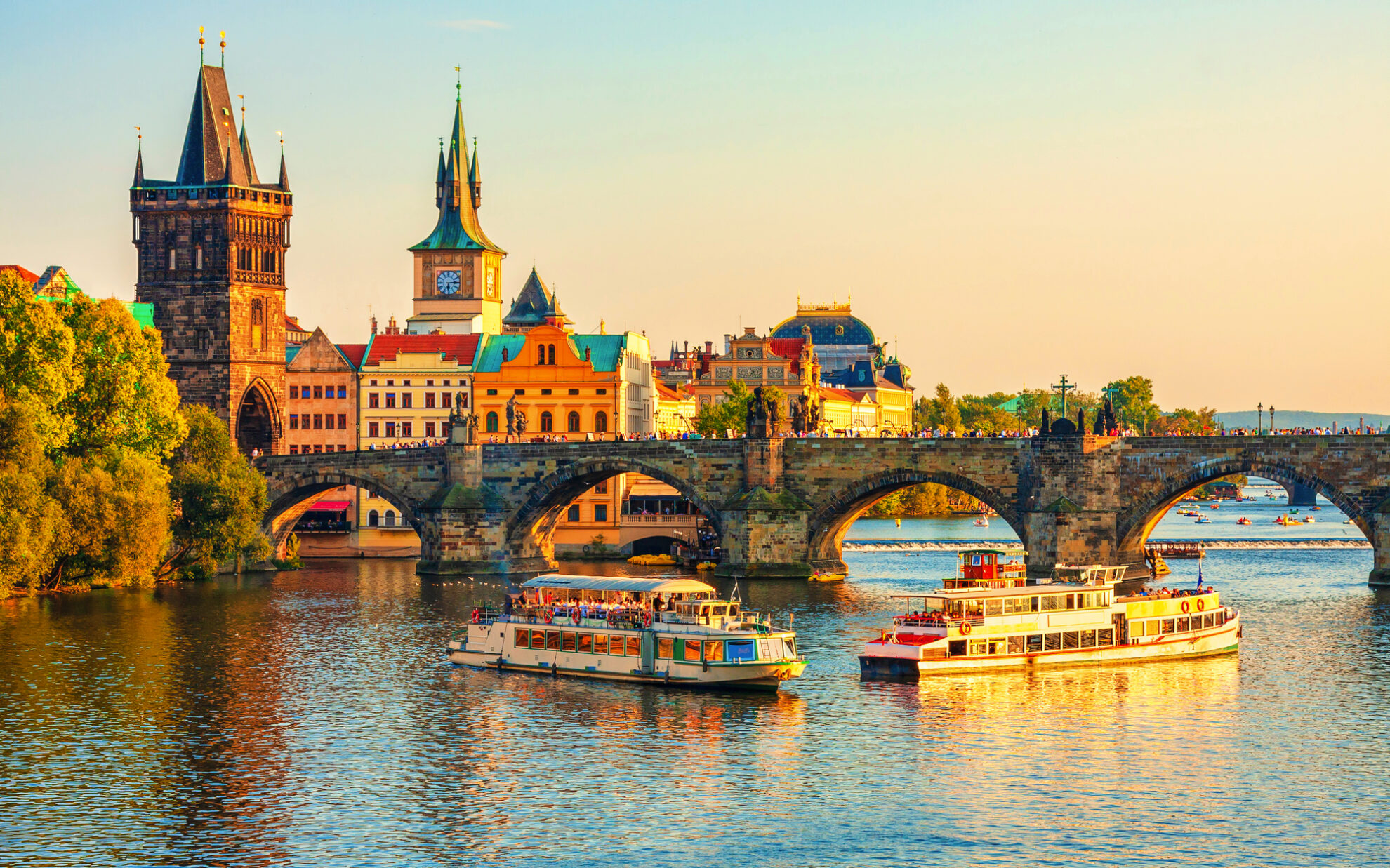 Romantische Abendstimmung an der Karlsbrücke in Prag mit Ausflugsschiffen auf der Moldau.