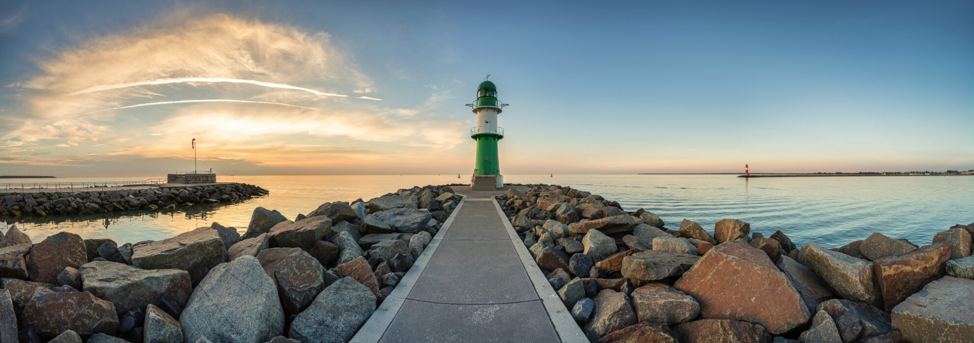 Leuchtturm am Hafen von Warnemünde bei Sonnenuntergang – maritimes Wahrzeichen an der Ostsee und beliebtes Ziel für Küsten-Busreisen.