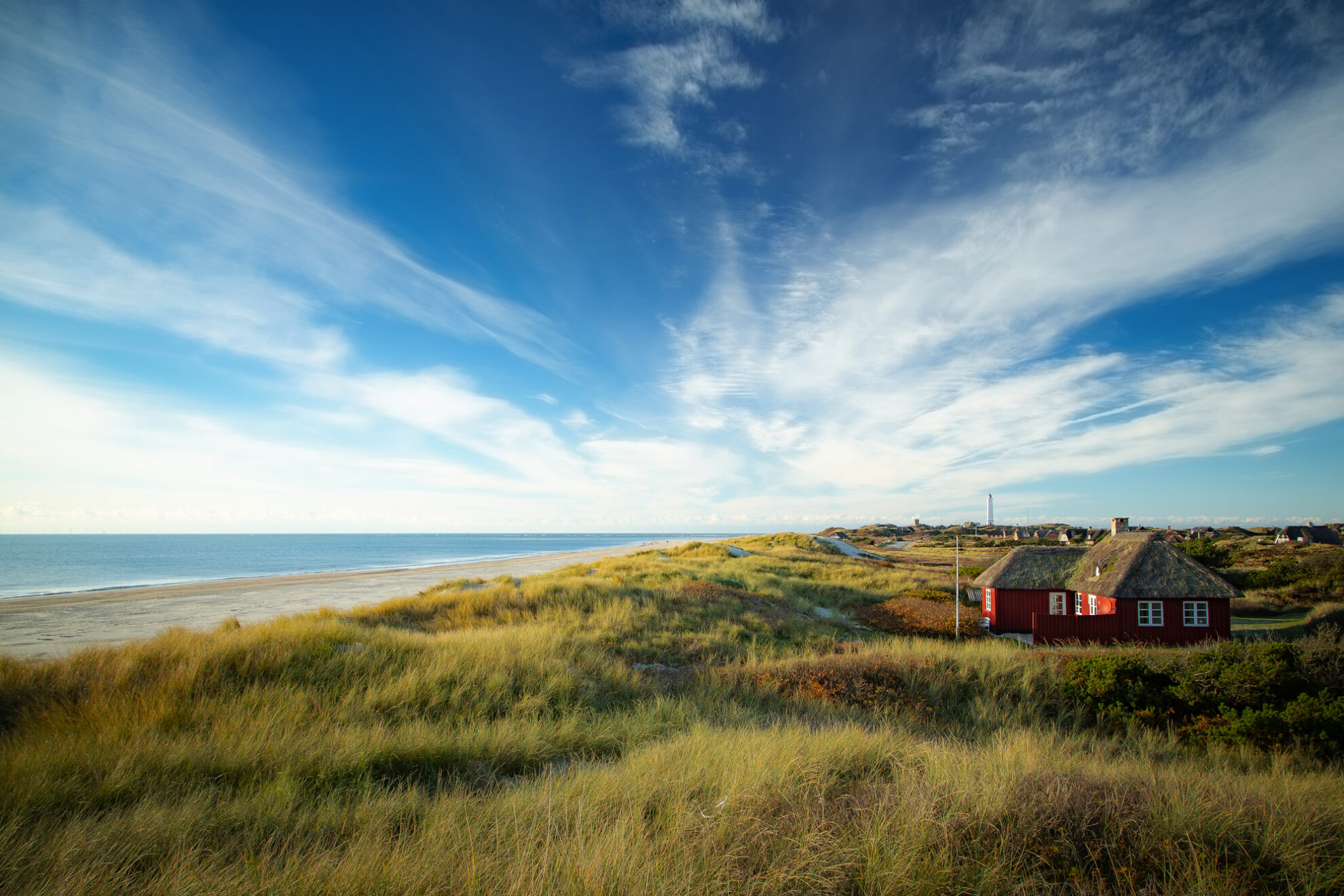 Idyllische Küstenlandschaft mit Dünen, Nordsee-Strand und rotem Ferienhaus – Urlaub am Meer in Dänemark genießen.