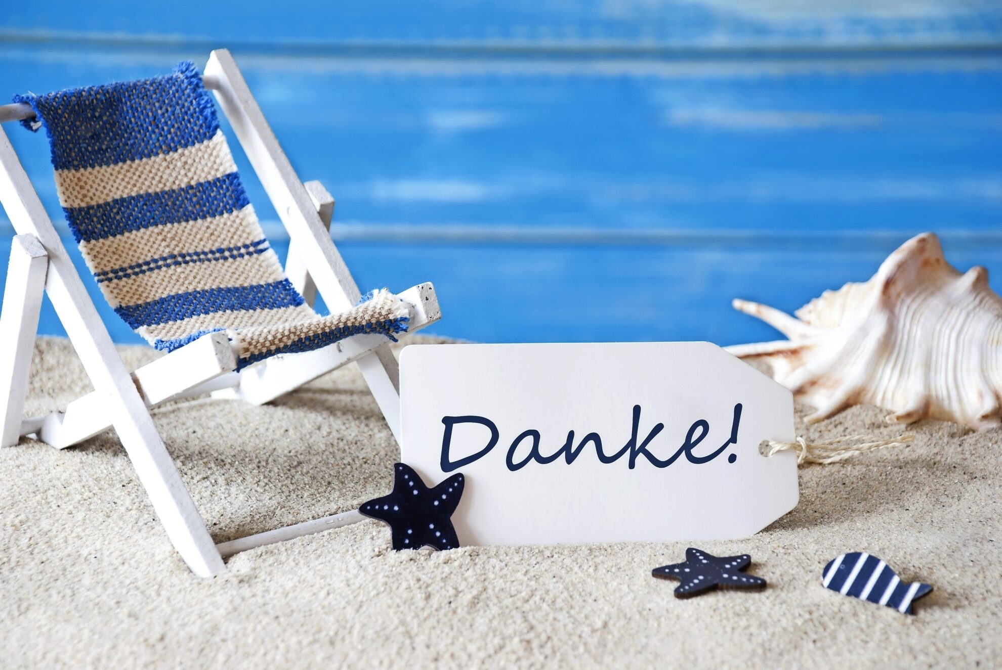 Maritime Dankeschön-Deko mit Mini-Liegestuhl im Sand, Muschel und Anhänger ‚Danke‘ – sommerliche Tischdekoration im Strand-Design.