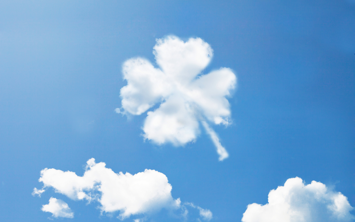 Wolke in Form eines vierblättrigen Kleeblatts am blauen Himmel.