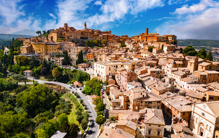 Mittelalterliche Stadt auf einem Hügel mit vielen engen Gassen und bäuerlicher Umgebung.