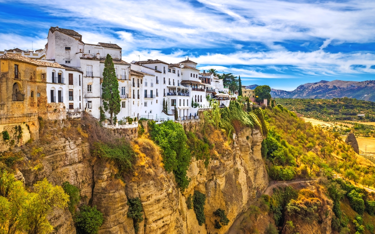 Weiße Gebäude auf einer Klippe mit Blick auf eine Landschaft und blauen Himmel.