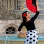 Frau in Flamenco-Kleidung mit rotem Fächer vor Brunnen.