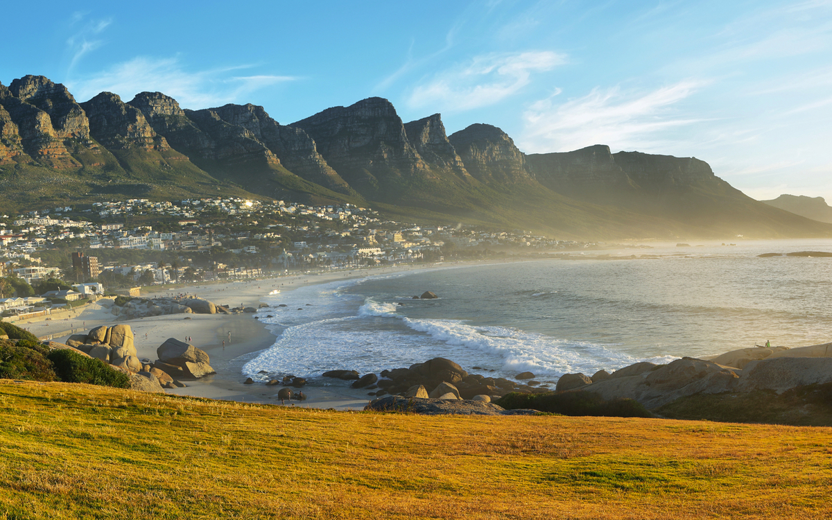 Küstenlandschaft mit Bergen und Stränden unter blauem Himmel.