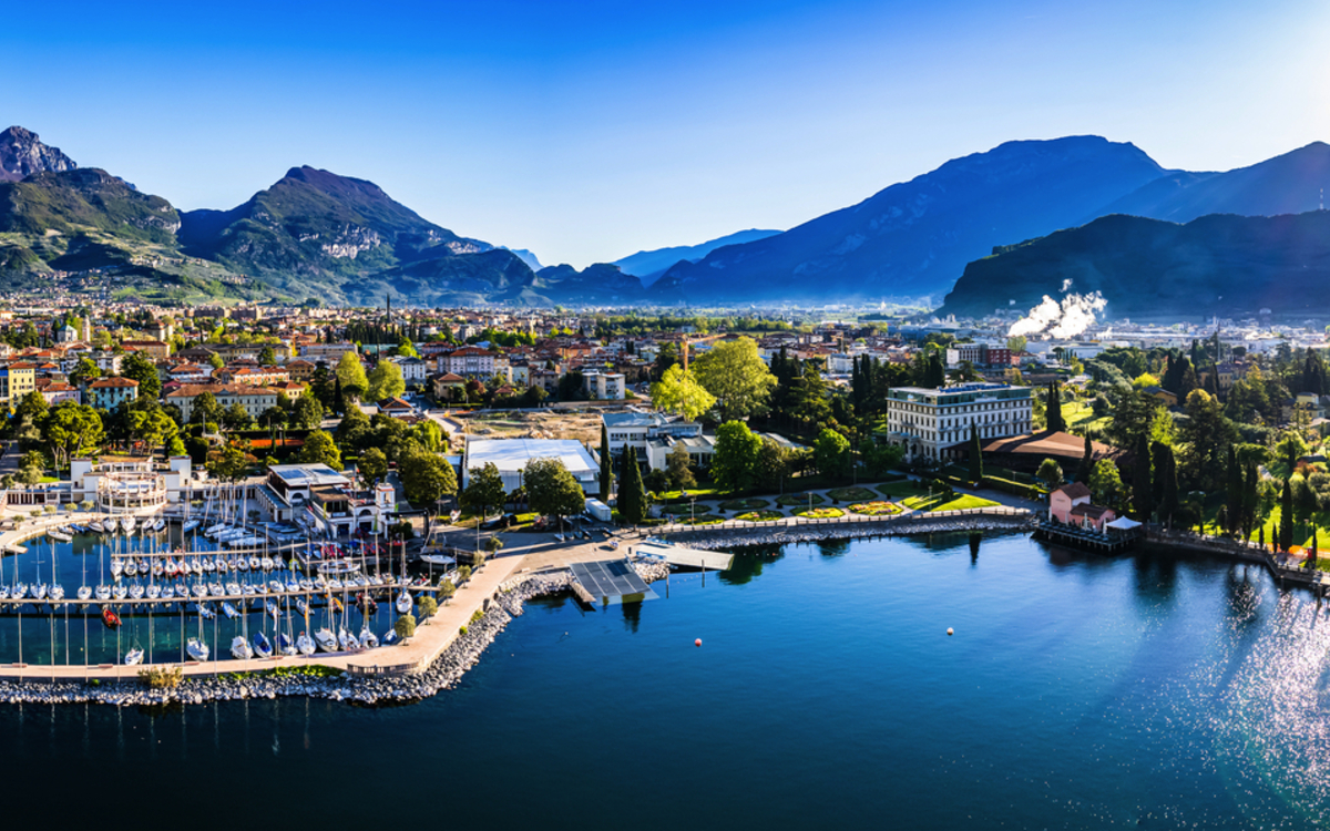 Panorama einer Stadt am See mit Bergen im Hintergrund bei strahlendem Sonnenschein.