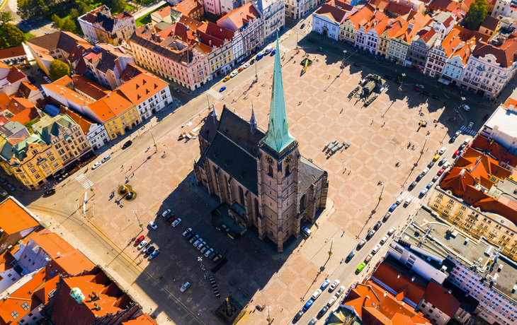 Luftaufnahme einer Kirche auf einem großen Platz mit umliegenden Gebäuden.