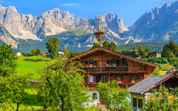 Traditionelles Almhaus in Going am Wilden Kaiser vor der Kulisse der Tiroler Alpen.