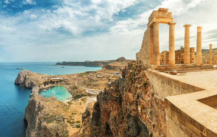 Alte Ruinen auf einer Klippe mit Meerblick im Hintergrund.