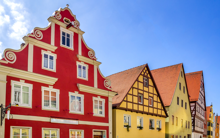 Historische Altstadt von Nördlingen in Bayern mit bunten Fachwerkhäusern und blauem Himmel.