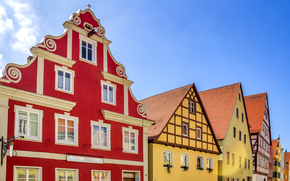 Historische Altstadt von Nördlingen in Bayern mit bunten Fachwerkhäusern und blauem Himmel.