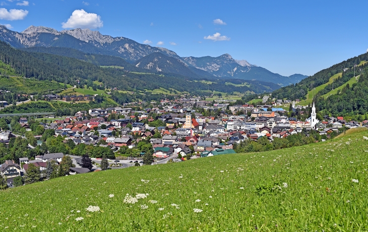Panorama einer Stadt in einem Tal mit Bergen im Hintergrund.