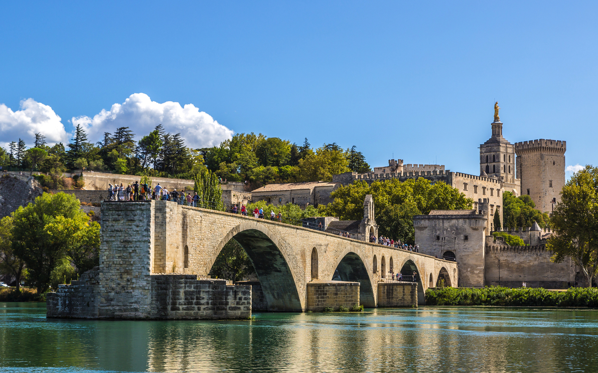 Steinbrücke über einen Fluss mit historischer Befestigungsanlage im Hintergrund.