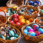 Bemalte Ostereier in bunten Farben in Weidenkörben auf einem Ostermarkt.