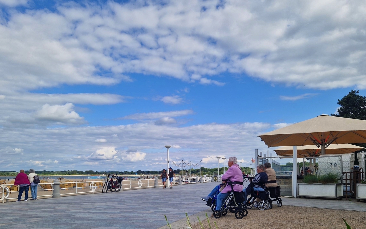 Menschen mit Rollatoren spazieren an der Strandpromenade in Travemünde.