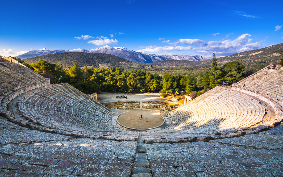 Antikes Amphitheater mit bewaldeter Berglandschaft im Hintergrund