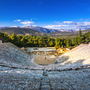 Antikes Amphitheater mit bewaldeter Berglandschaft im Hintergrund