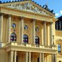 Fassade der Staatsoper Prag mit Säulen und Skulpturen bei Sonnenuntergang.