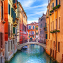 Kanal in Venedig mit bunten Häusern und einer kleinen Brücke über dem Wasser.