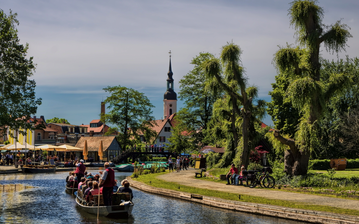 Bootsfahrt auf einem Fluss in einer malerischen Stadt mit Kirche und Bäumen.