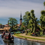 Bootsfahrt auf einem Fluss in einer malerischen Stadt mit Kirche und Bäumen.