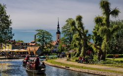 Bootsfahrt auf einem Fluss in einer malerischen Stadt mit Kirche und Bäumen.