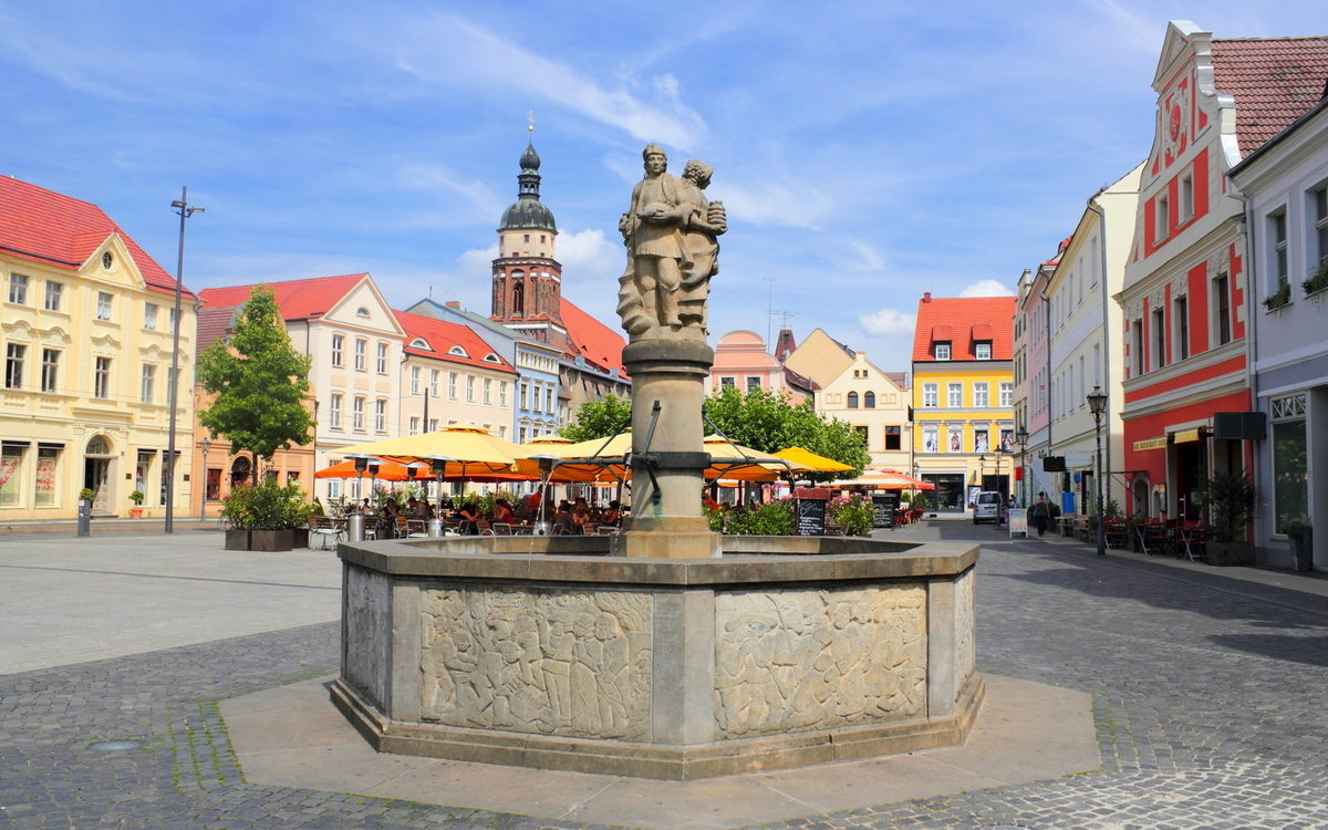 Marktplatz mit Brunnen und umgebenden historischen Gebäuden bei Sonnenschein