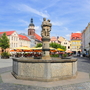Marktplatz mit Brunnen und umgebenden historischen Gebäuden bei Sonnenschein