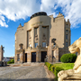 Historisches Gebäude mit Skulpturen und blauem Himmel im Hintergrund.