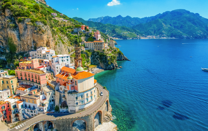 Küstenstadt mit bunten Häusern auf Klippen und Blick aufs blaue Meer.