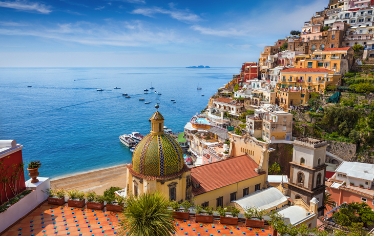 Küstenstadt mit bunten Häusern und blauem Meer im Hintergrund.