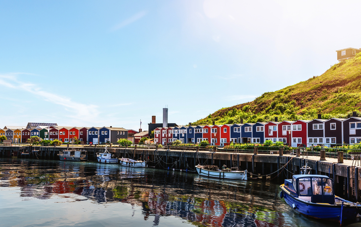 Bunte Häuser an einem Hafen mit Booten unter blauem Himmel.