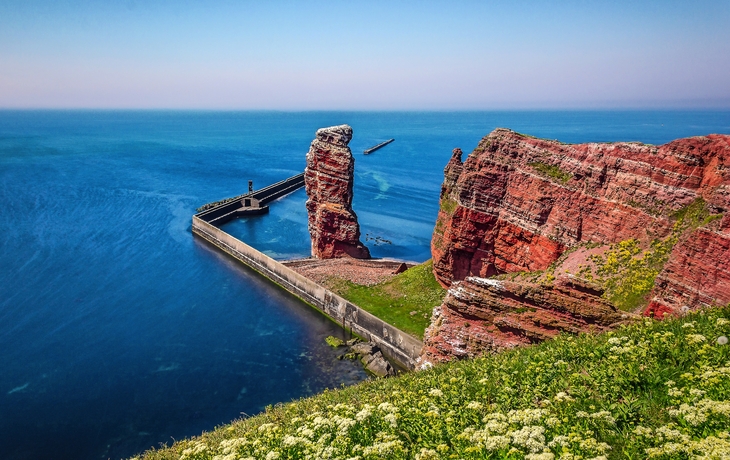 Klippenlandschaft mit rotem Felsen und blauem Meer bei Helgoland.