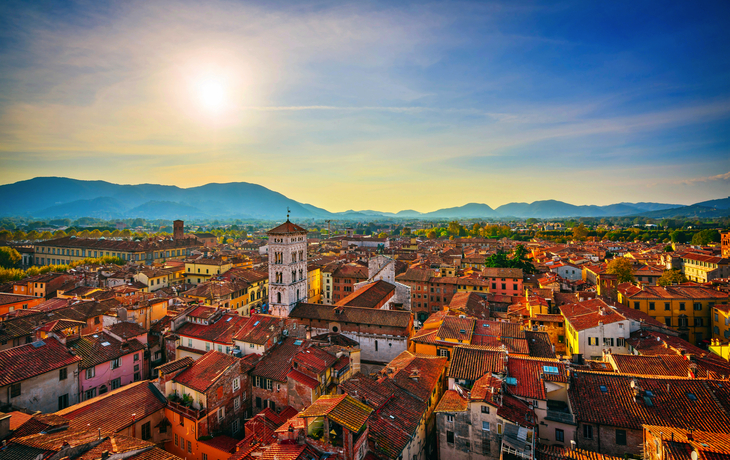 Stadtansicht bei Sonnenuntergang mit Bergen im Hintergrund.