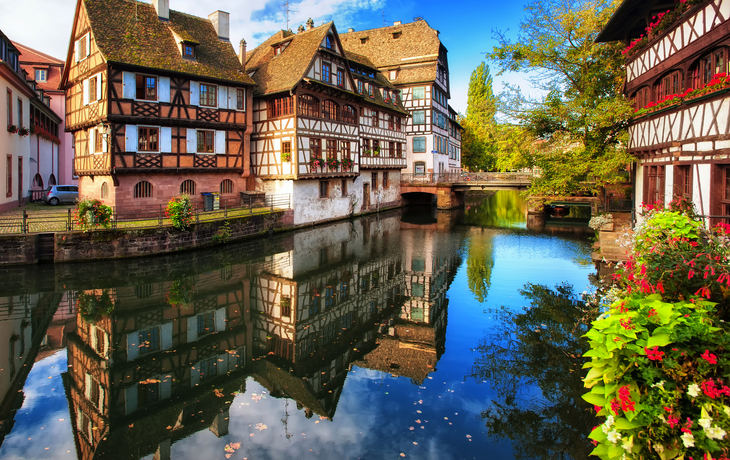 Fachwerkhäuser an einem Kanal in einer malerischen Altstadt mit Herbstlaub.