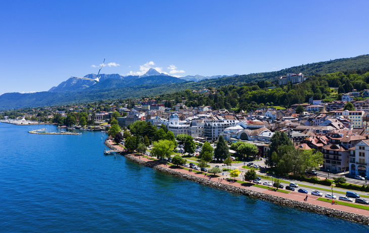 Drohnenansicht einer Küstenstadt mit Bergen im Hintergrund an einem klaren Tag.
