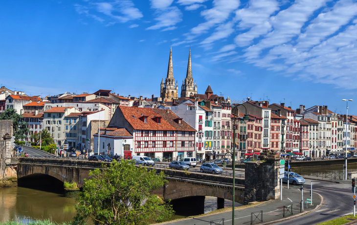 Blick auf Stadt mit Fluss, Brücke und Kirchen im Hintergrund.