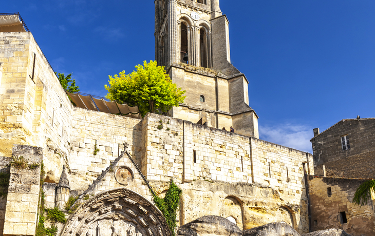 Kirche aus Stein mit hohem Turm und alten Fassaden unter blauem Himmel.