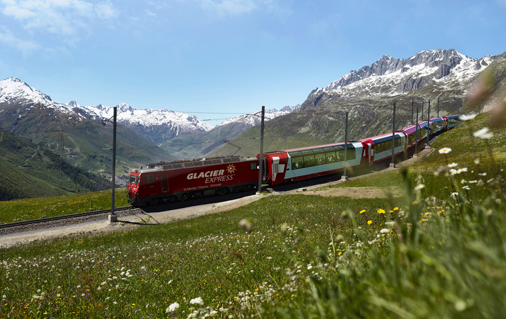 Glacier Express der Rhätischen Bahn am Oberalppass vor Alpenpanorama.