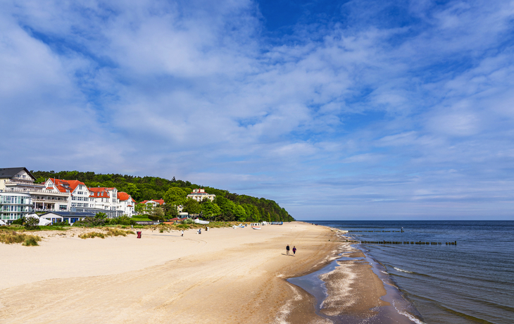 Blick auf den Strand in Bansin auf der Insel Usedom mit der Ostsee und Wohnhäusern im Hintergrund.