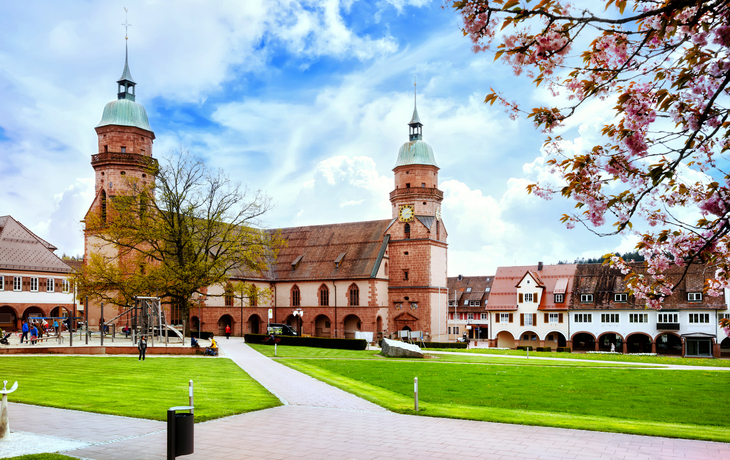 Historischer Platz mit Gebäuden und Kirchtürmen an einem sonnigen Tag.