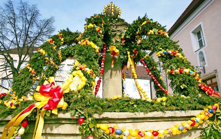 Brunnen mit buntem Osterschmuck aus Eiern und Pflanzen.