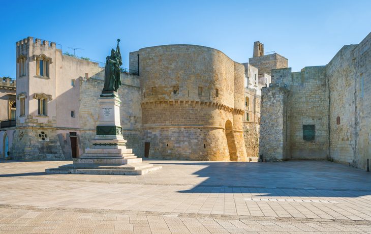 Historische Festung mit Statue auf einem Platz an einem klaren Tag.