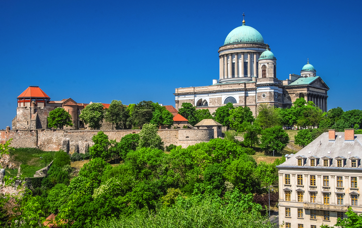 Basilika und alte Festung auf Hügel mit Bäumen und historischem Gebäude im Vordergrund