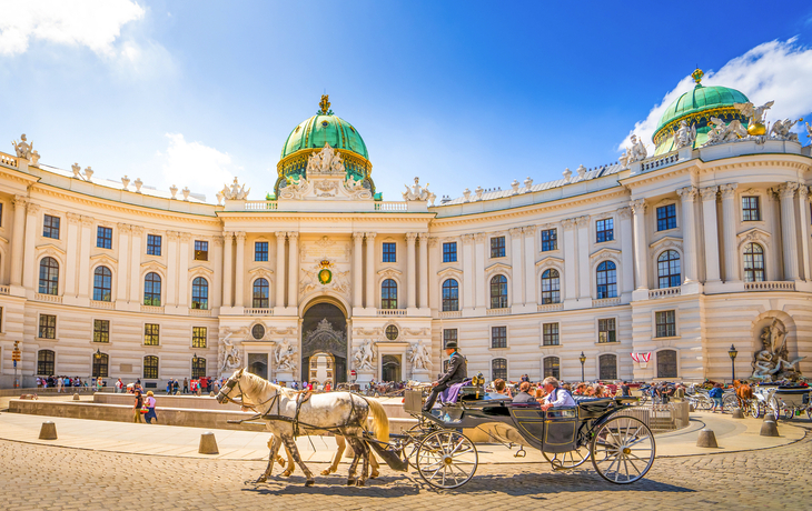 Die Hofburg in Wien mit einer Pferdekutsche auf dem Heldenplatz.