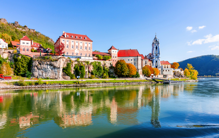 Historische Gebäude am Ufer eines Flusses bei sonnigem Wetter.