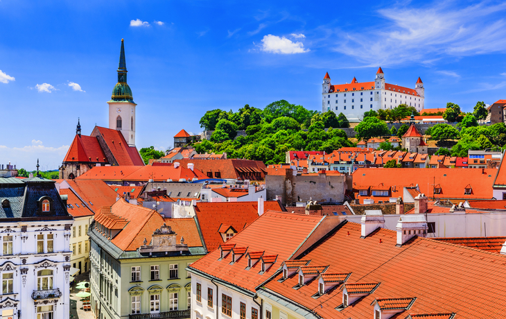 Blick auf Bratislavas Altstadt mit Burg und Kirche unter blauem Himmel.
