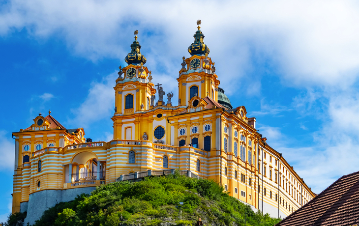 Gelbe Barockkirche auf einem Hügel unter blauem Himmel.
